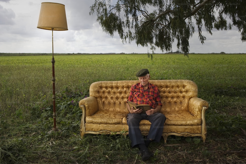 a man sitting on a couch in a field