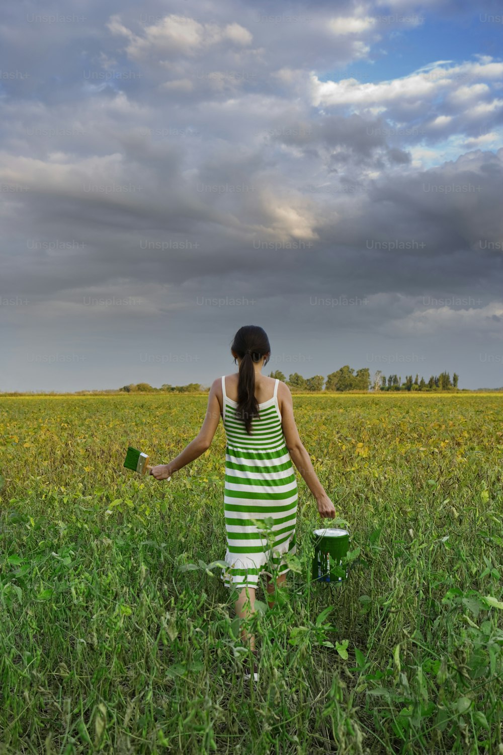a woman in a green and white striped dress standing in a field