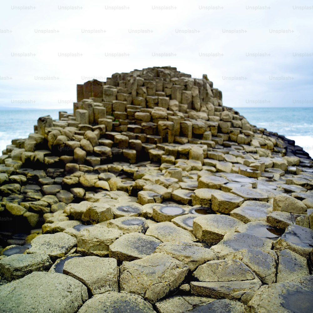 uma grande pilha de rochas sentada em cima de uma praia