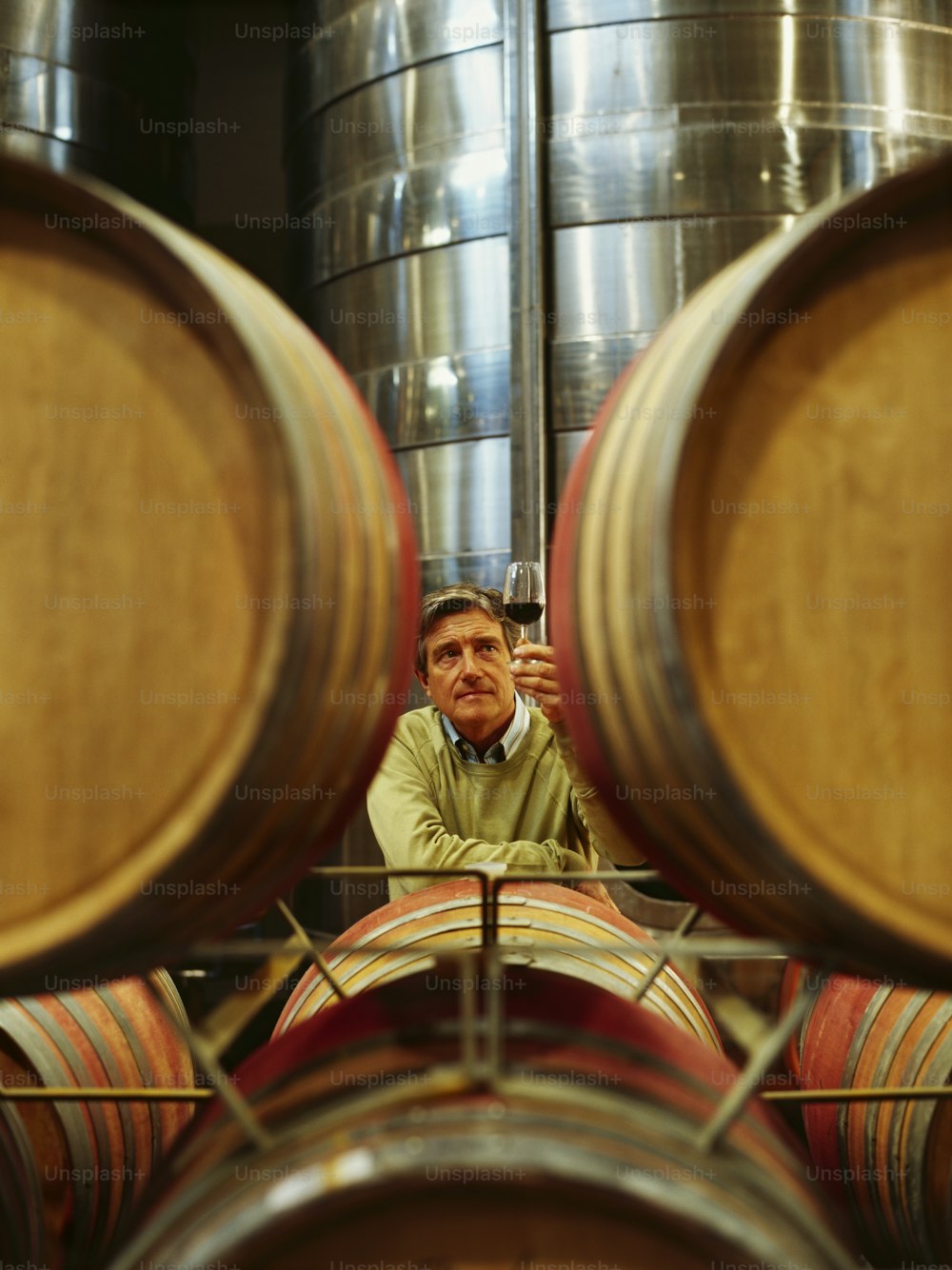 a man sitting in front of a bunch of wine barrels