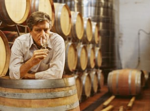 a man drinking a glass of wine in a wine cellar