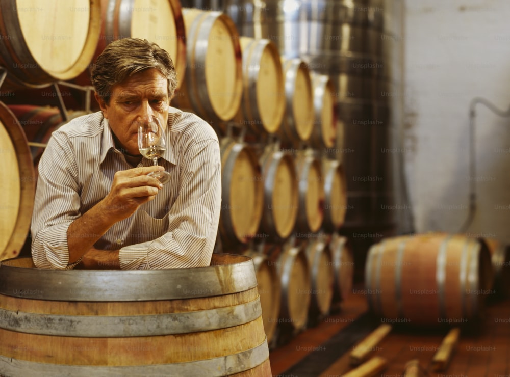 Un homme buvant un verre de vin dans une cave à vin
