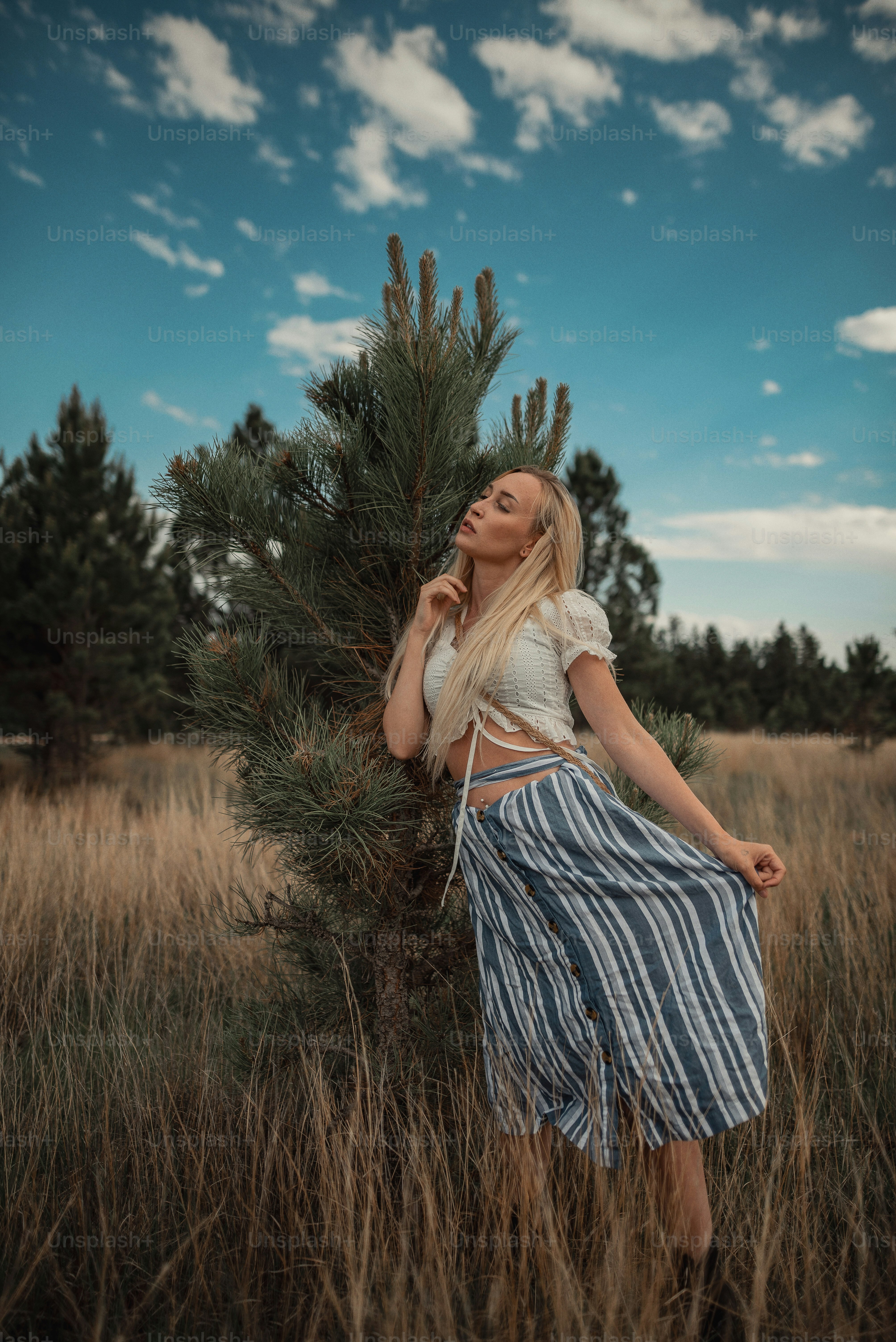 a woman standing in a field next to a tree