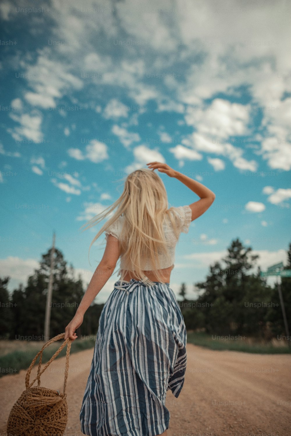 a woman walking down a dirt road carrying a basket