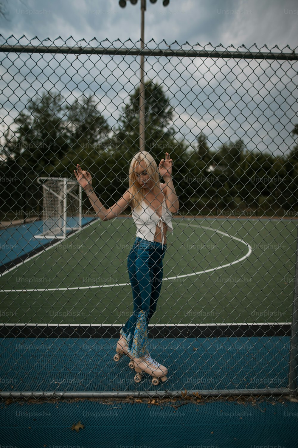 a woman riding a skateboard through a chain link fence