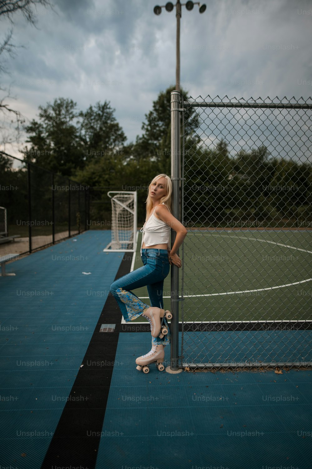 a woman leaning against a fence on a tennis court