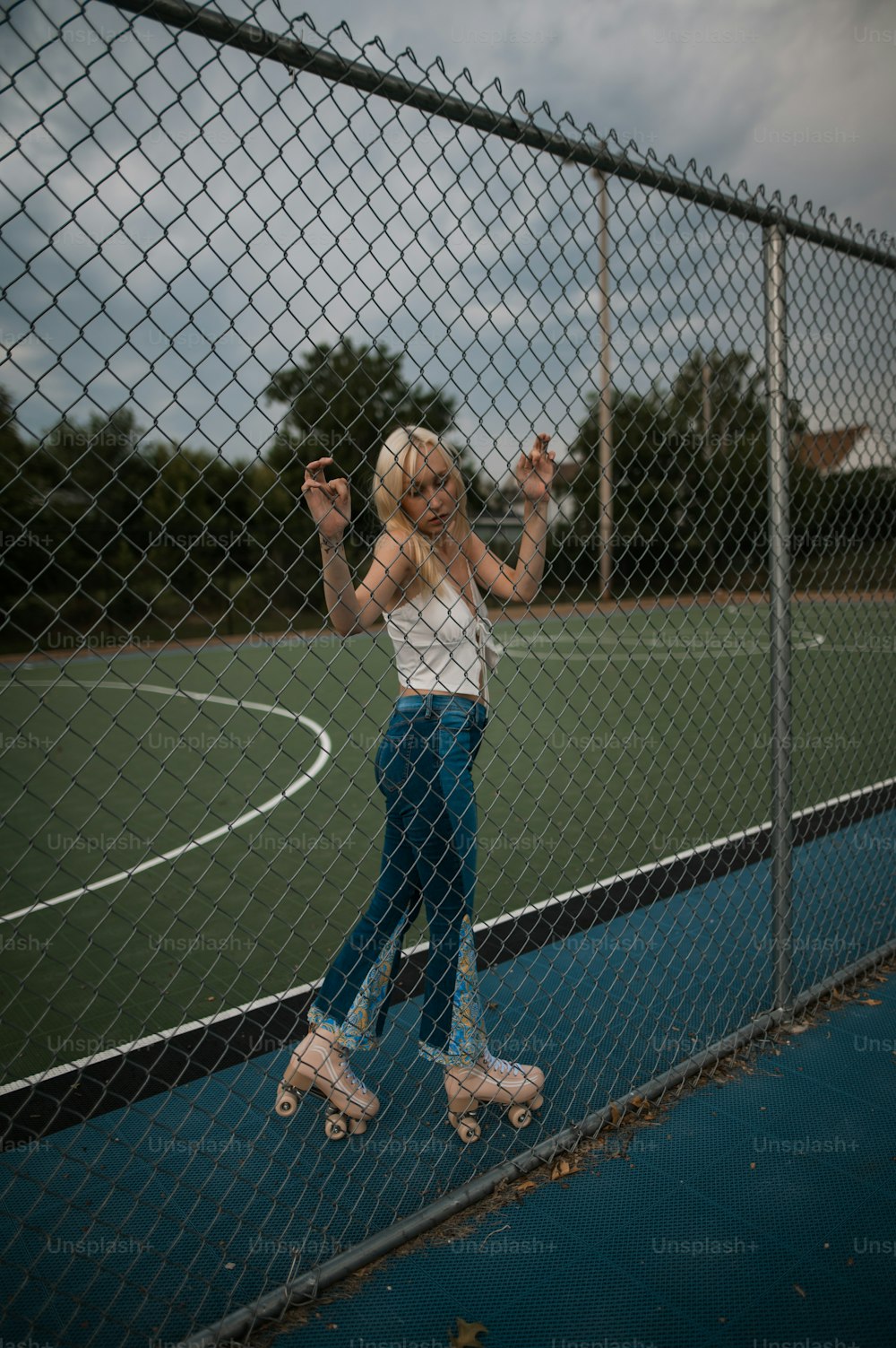 a woman standing on roller blades in front of a fence