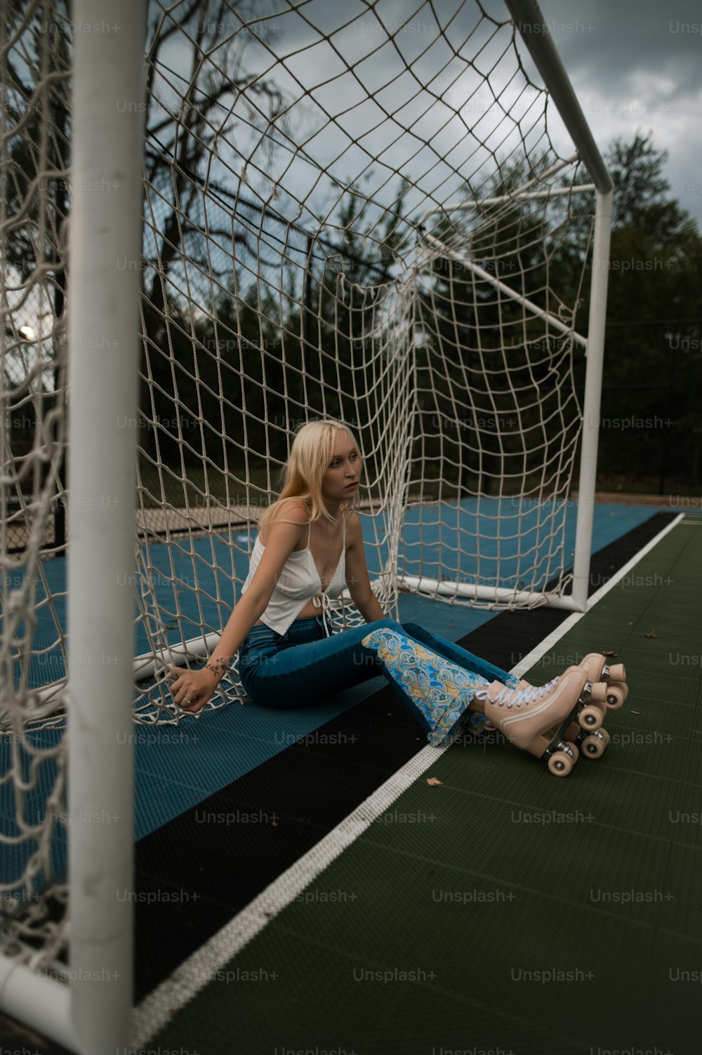 a woman sitting on the ground in front of a soccer goal