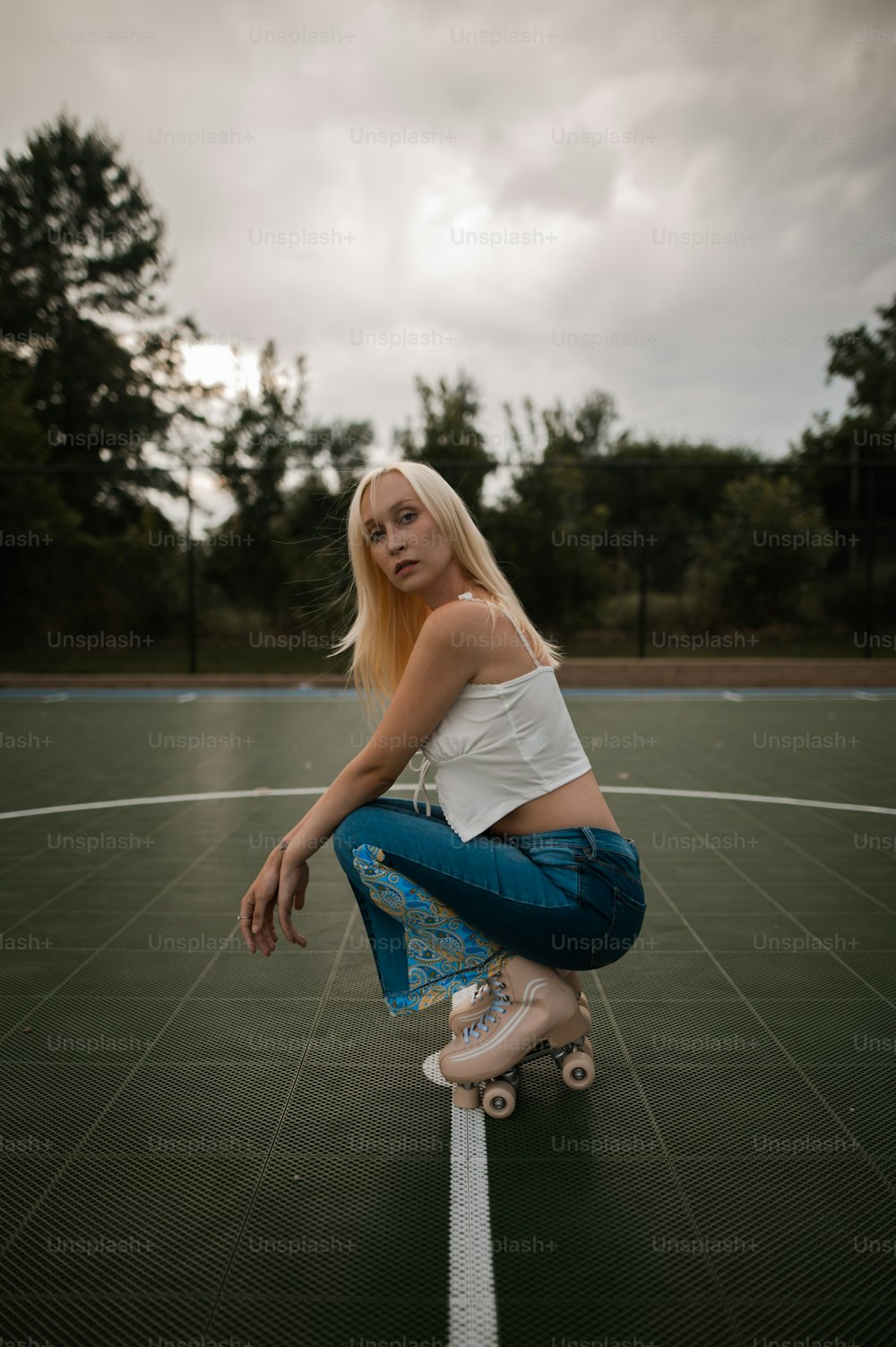 a woman sitting on a skateboard on a tennis court