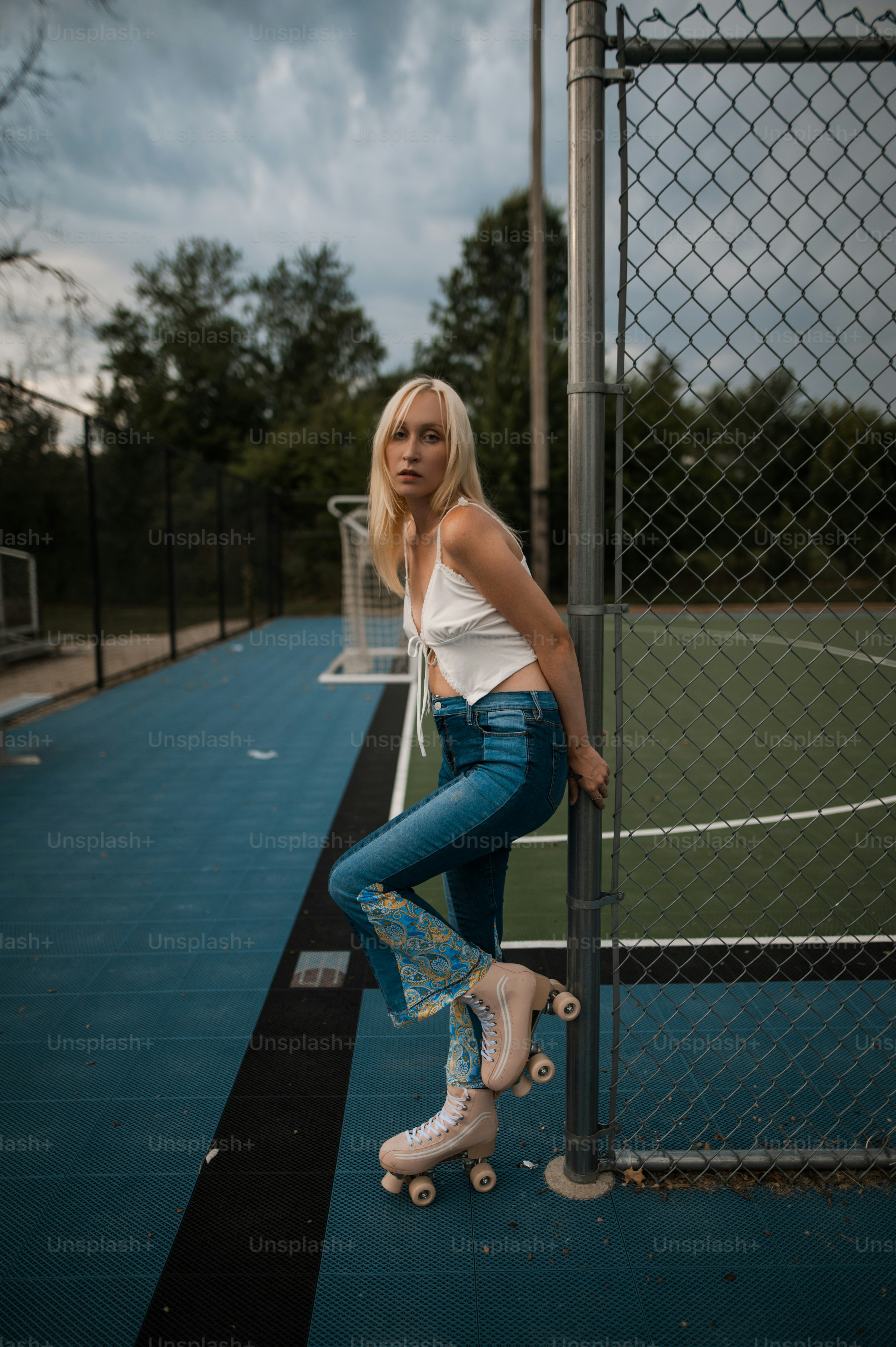 Una mujer apoyada contra una valla con una patineta