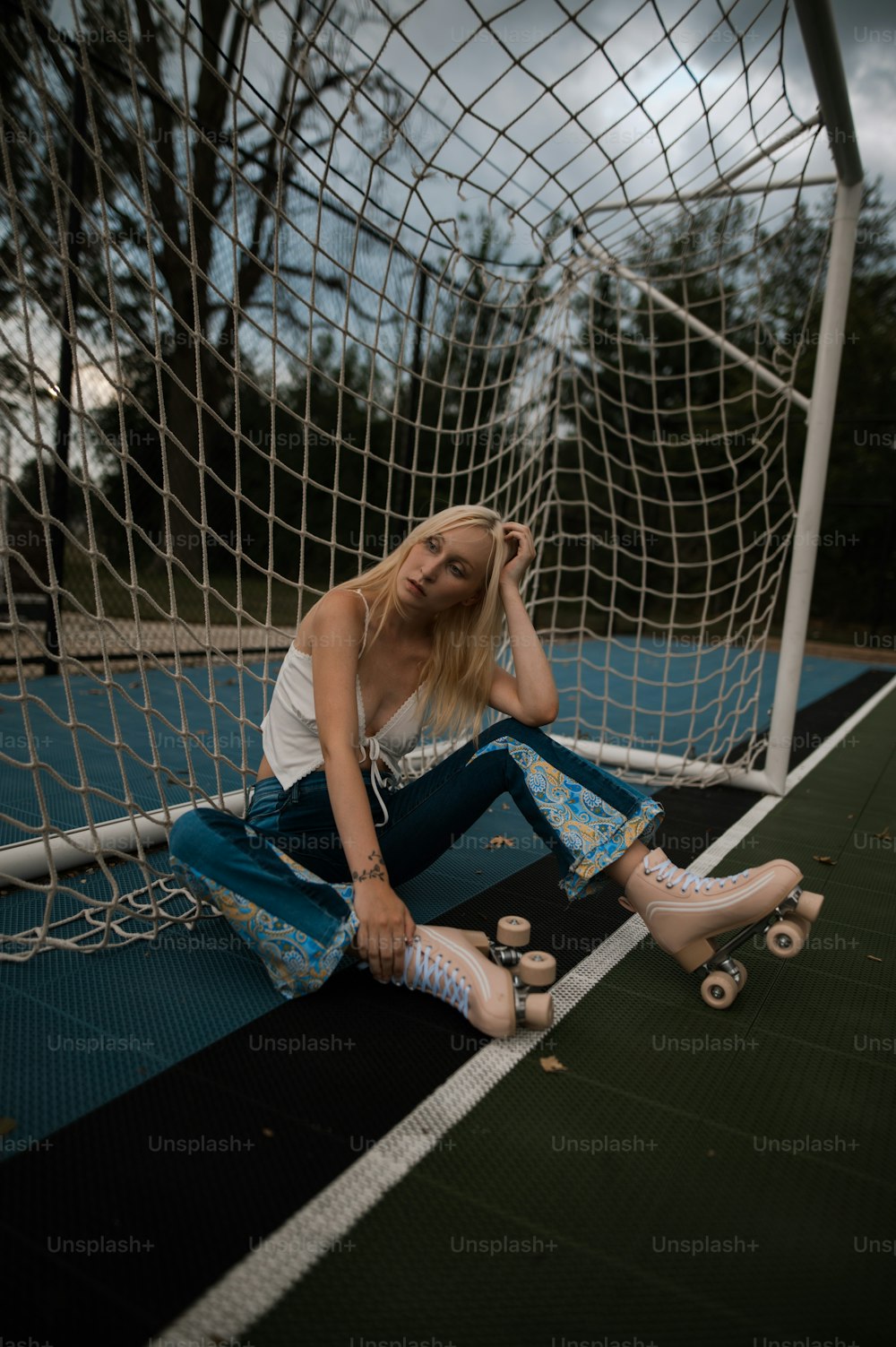 a woman sitting on the ground next to a soccer goal