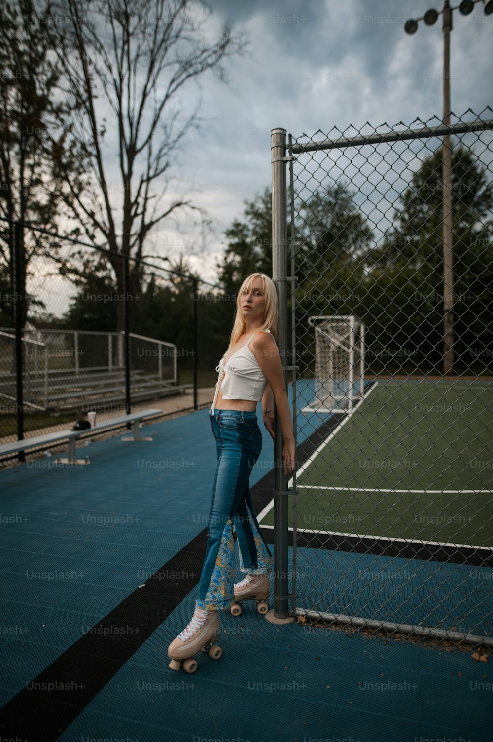 a woman leaning against a fence on a skateboard
