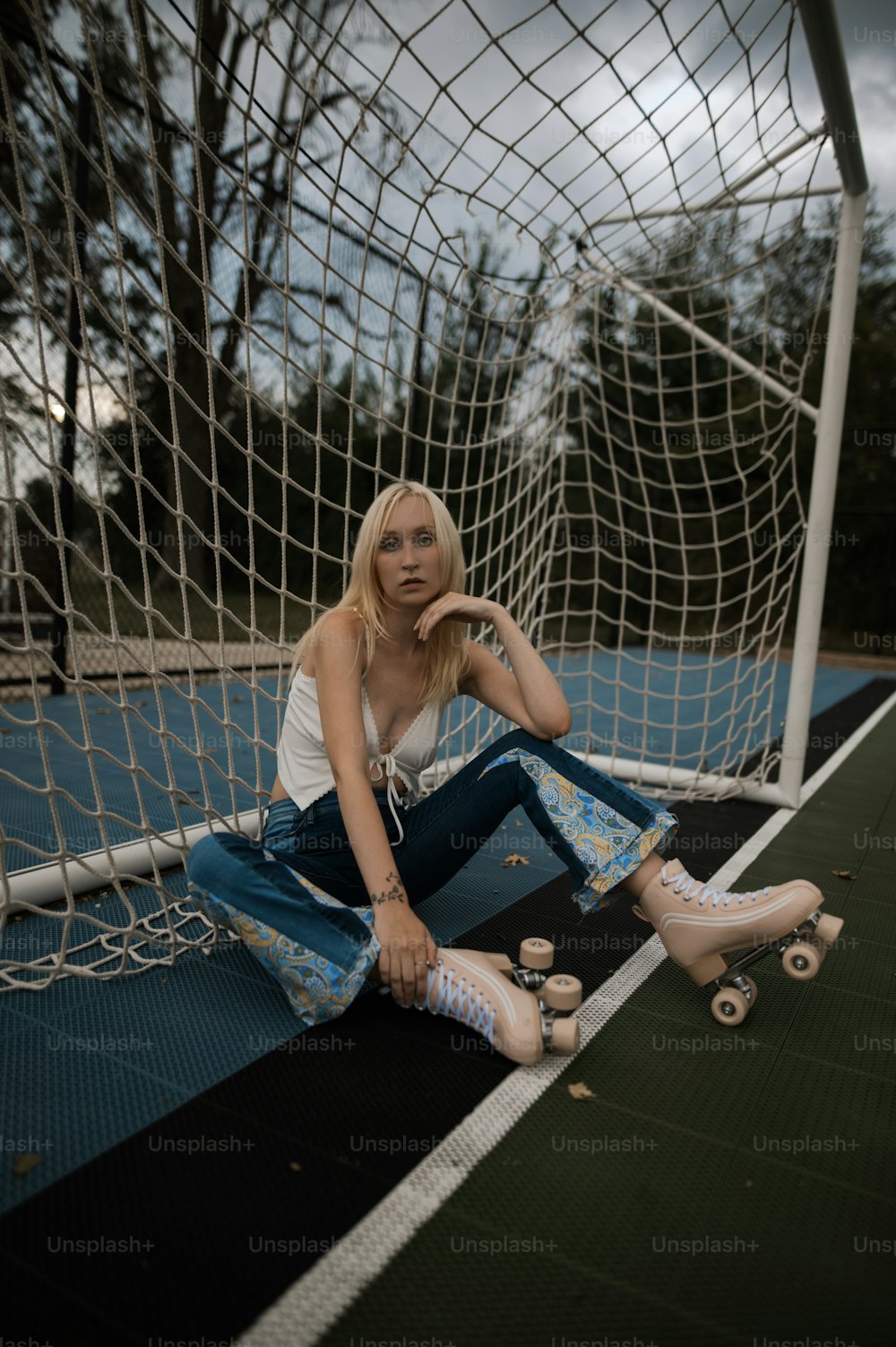 Una donna seduta a terra accanto a una rete da calcio