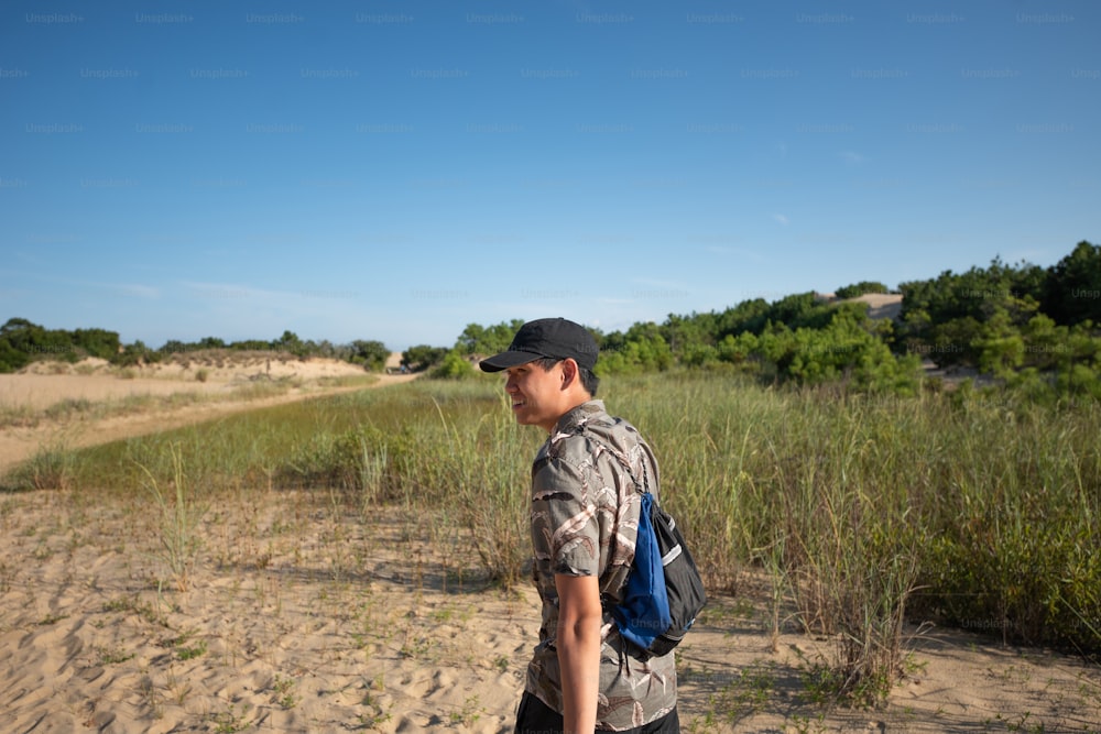 Um homem com uma mochila está de pé na areia