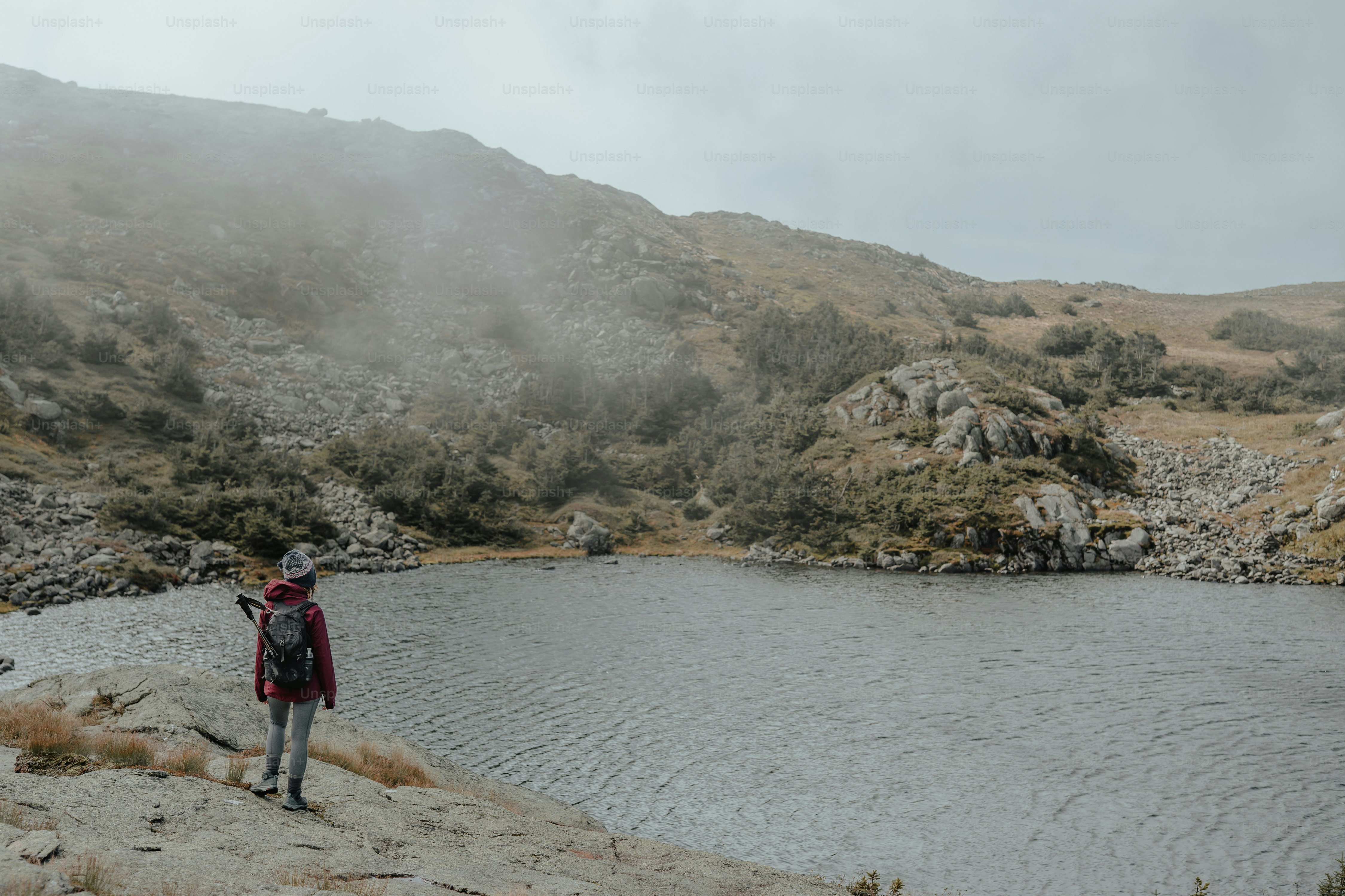 a person standing on a hill next to a body of water