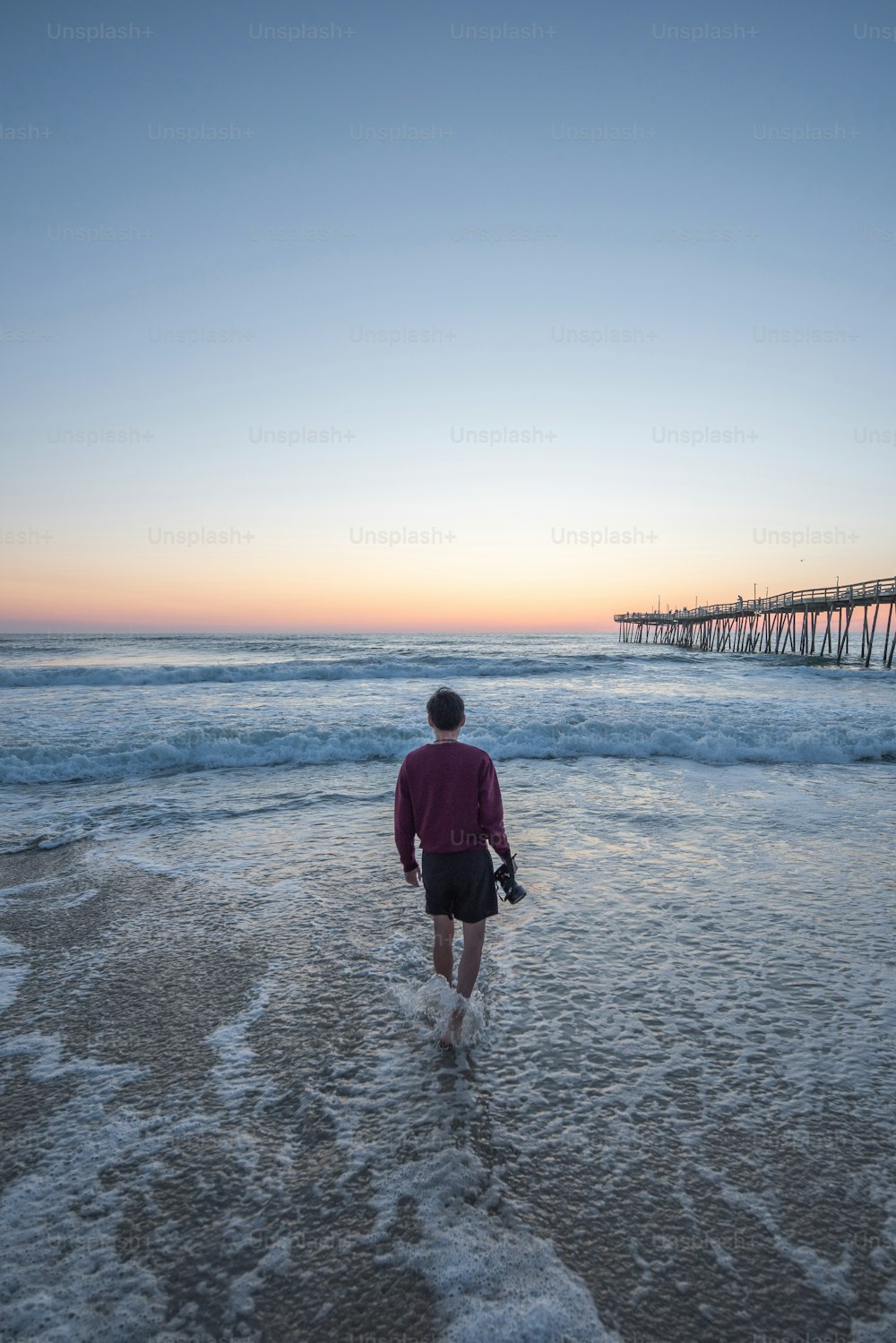 a person walking into the ocean at sunset