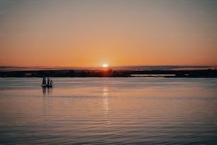 un voilier dans un plan d’eau au coucher du soleil