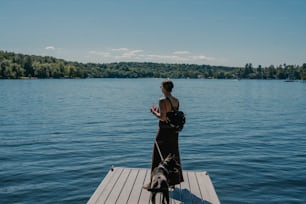 a woman standing on a dock next to a dog