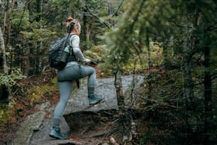 a woman with a backpack sitting on a rock in the woods