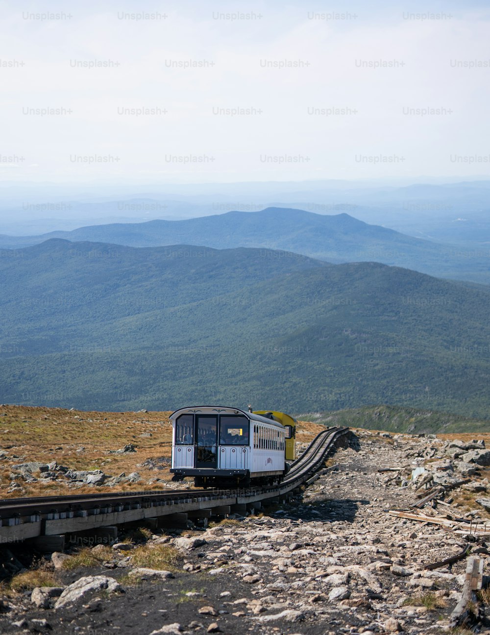 um trem em uma trilha com montanhas ao fundo