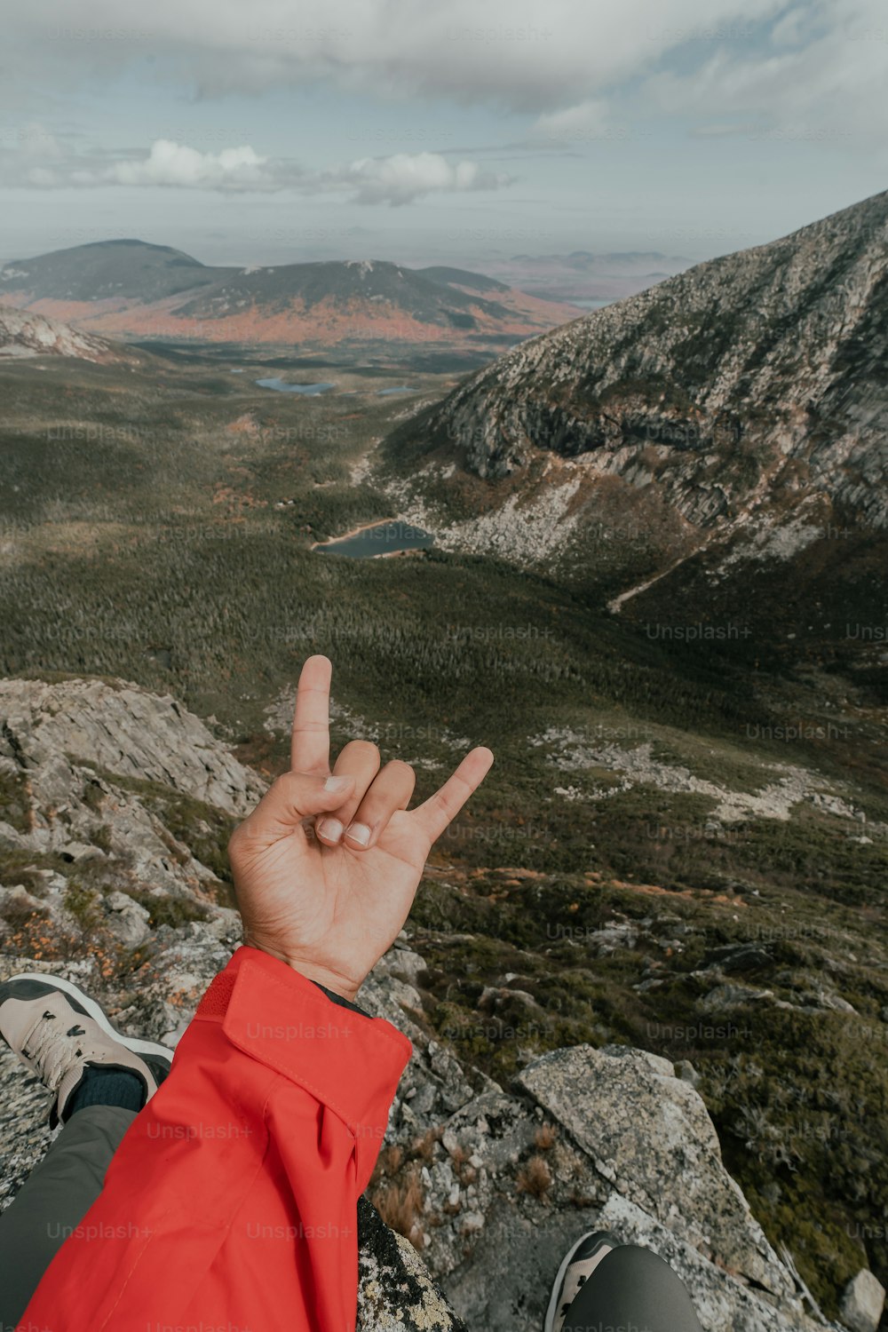 Una persona sentada en la cima de una montaña haciendo un signo de paz