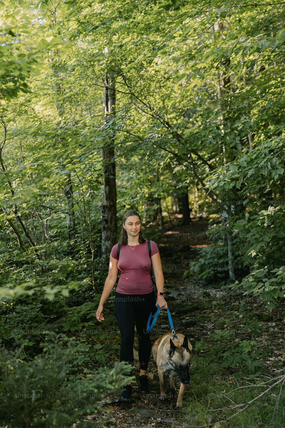 a woman walking her dog through the woods