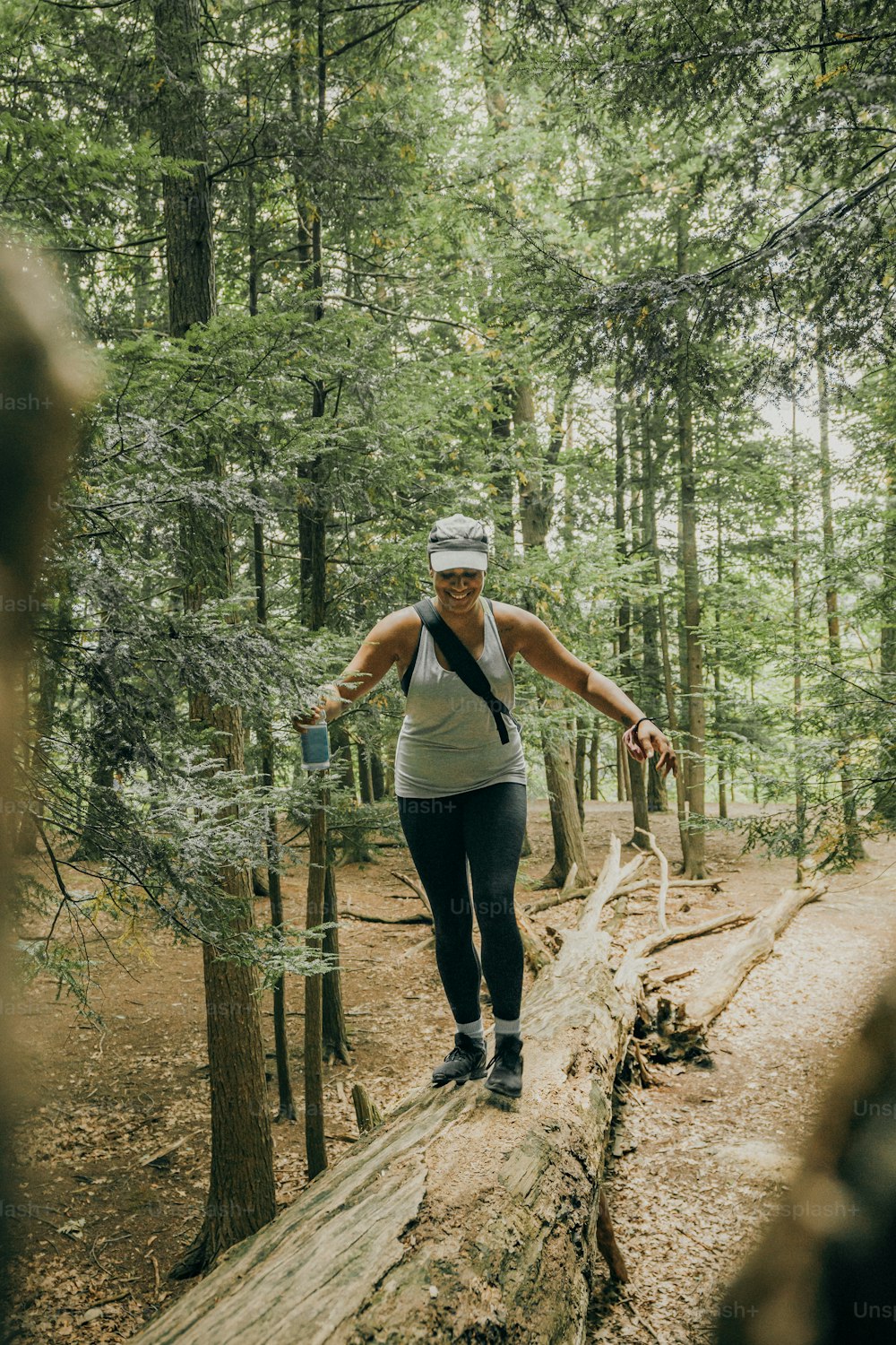a woman standing on a log in the woods