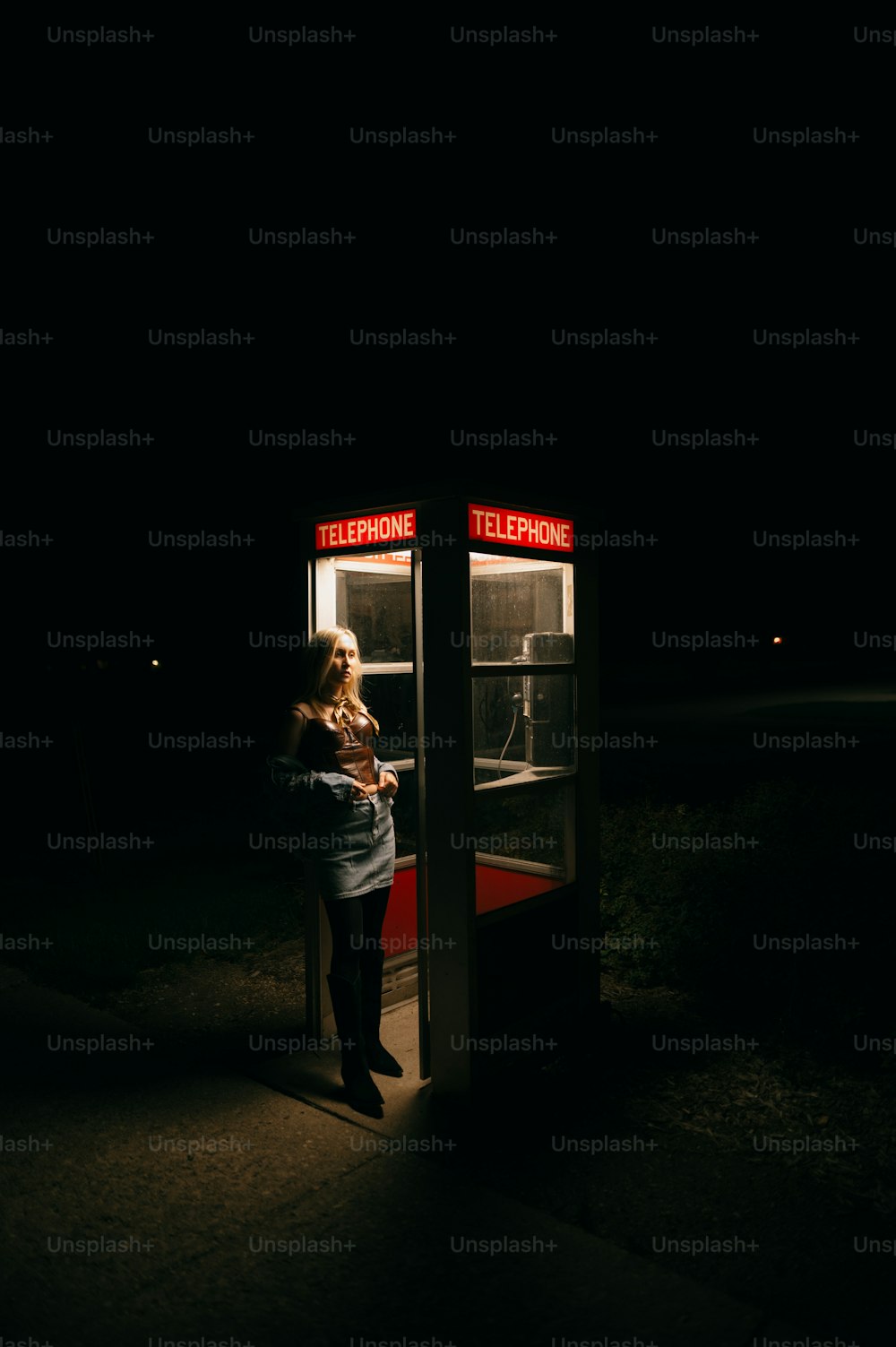 uma mulher em frente a uma cabine telefônica