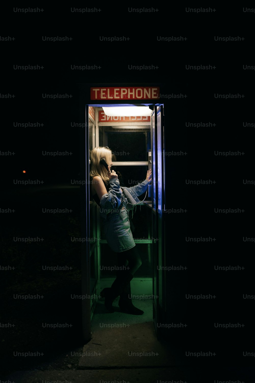 Una mujer parada frente a una cabina telefónica