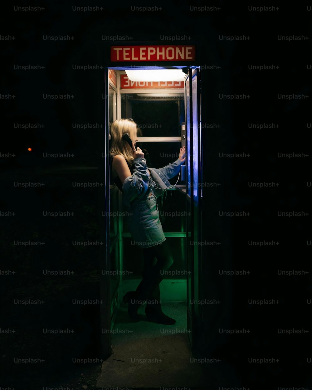 uma mulher em frente a uma cabine telefônica