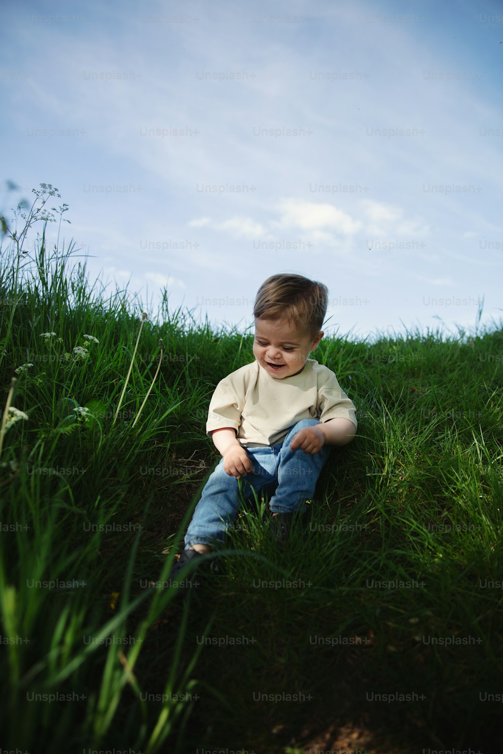 a little boy that is sitting in the grass