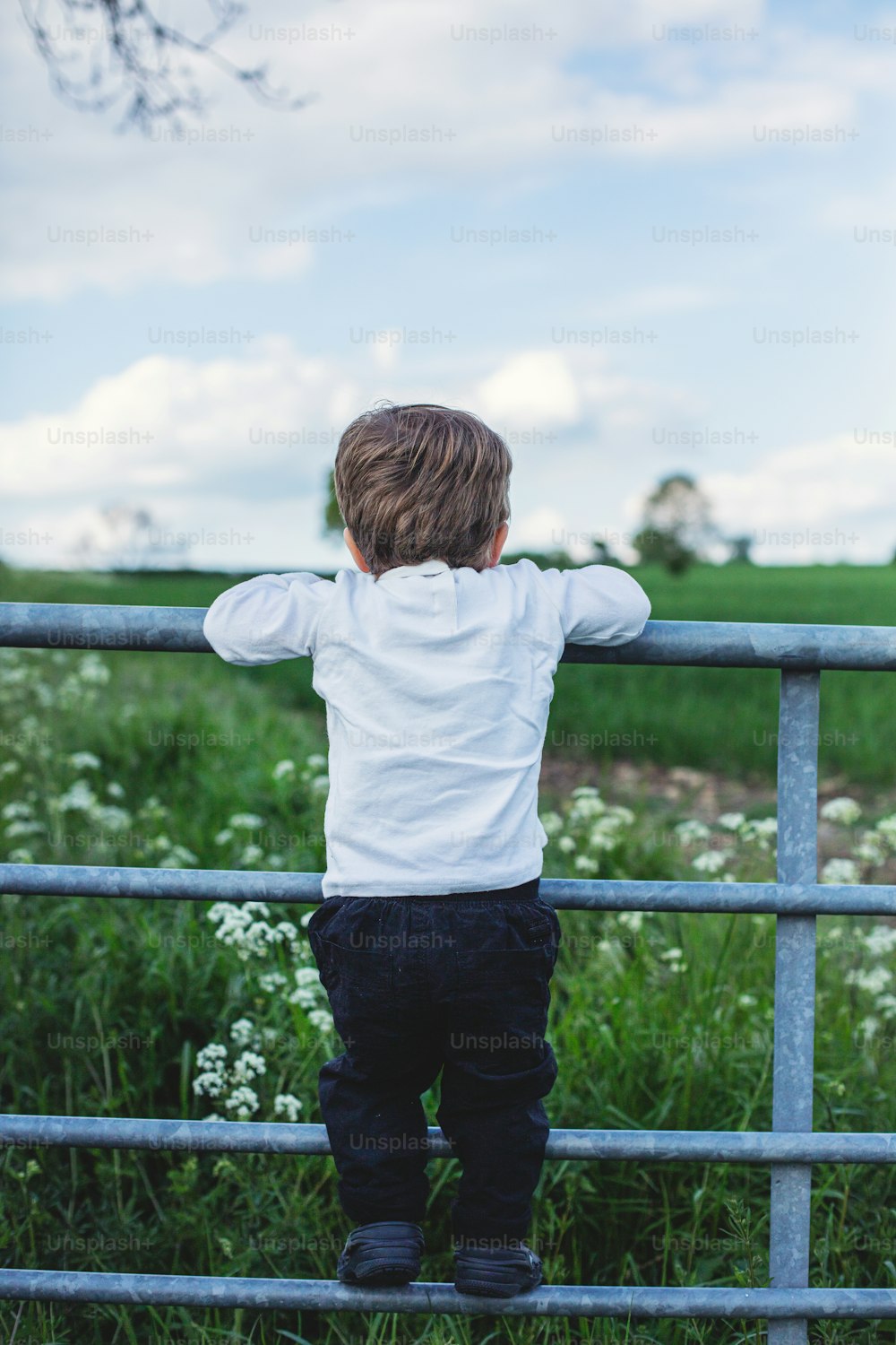 Un niño pequeño que está parado en una cerca