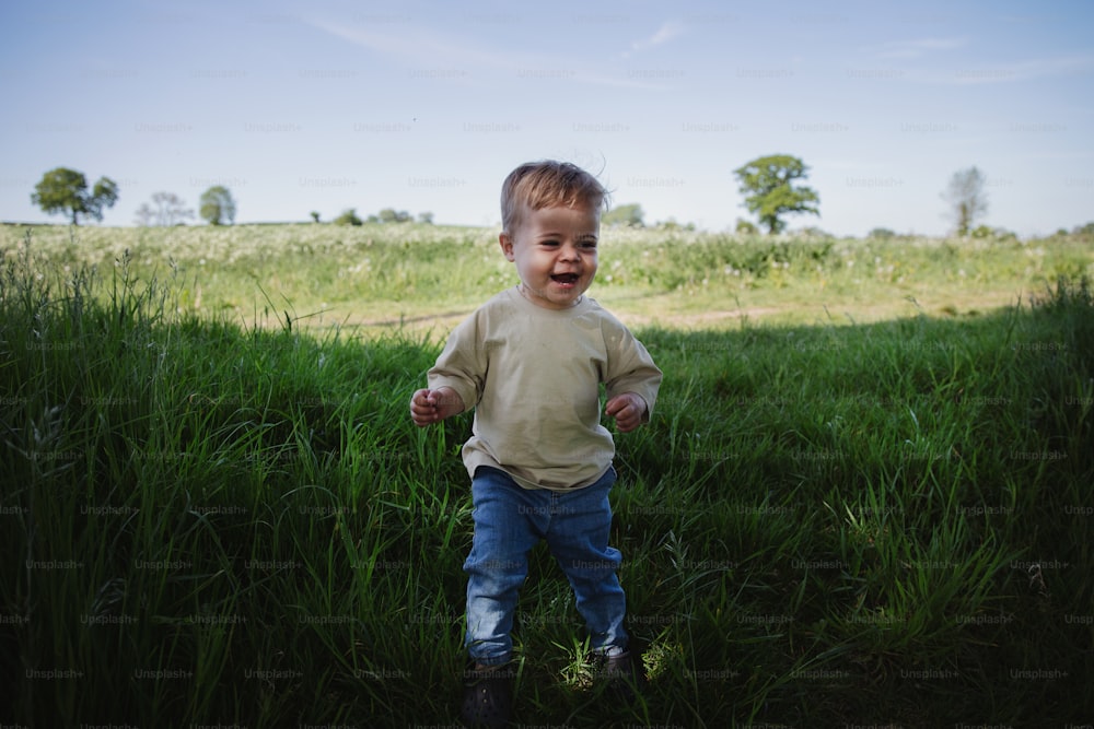 a little boy running through a field of tall grass