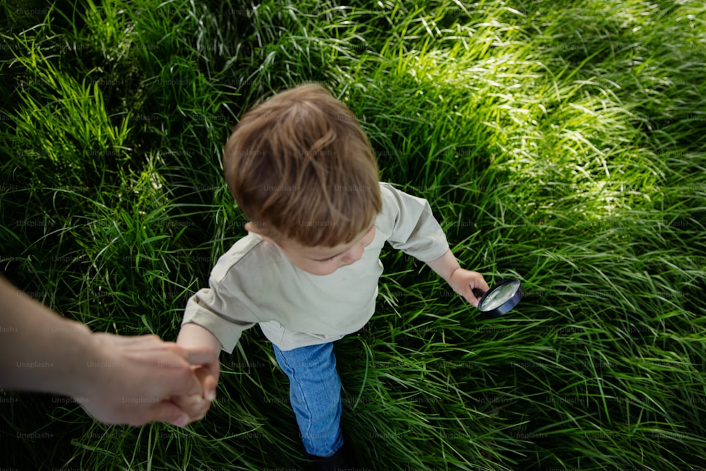 a little boy holding a cell phone in a field