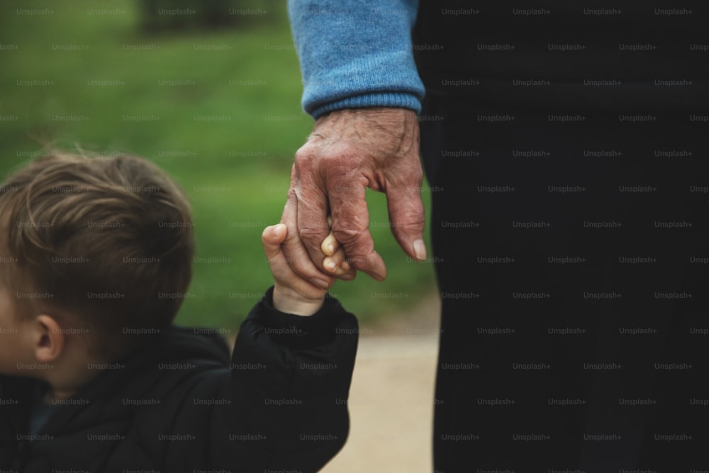 an older person holding the hand of a young child