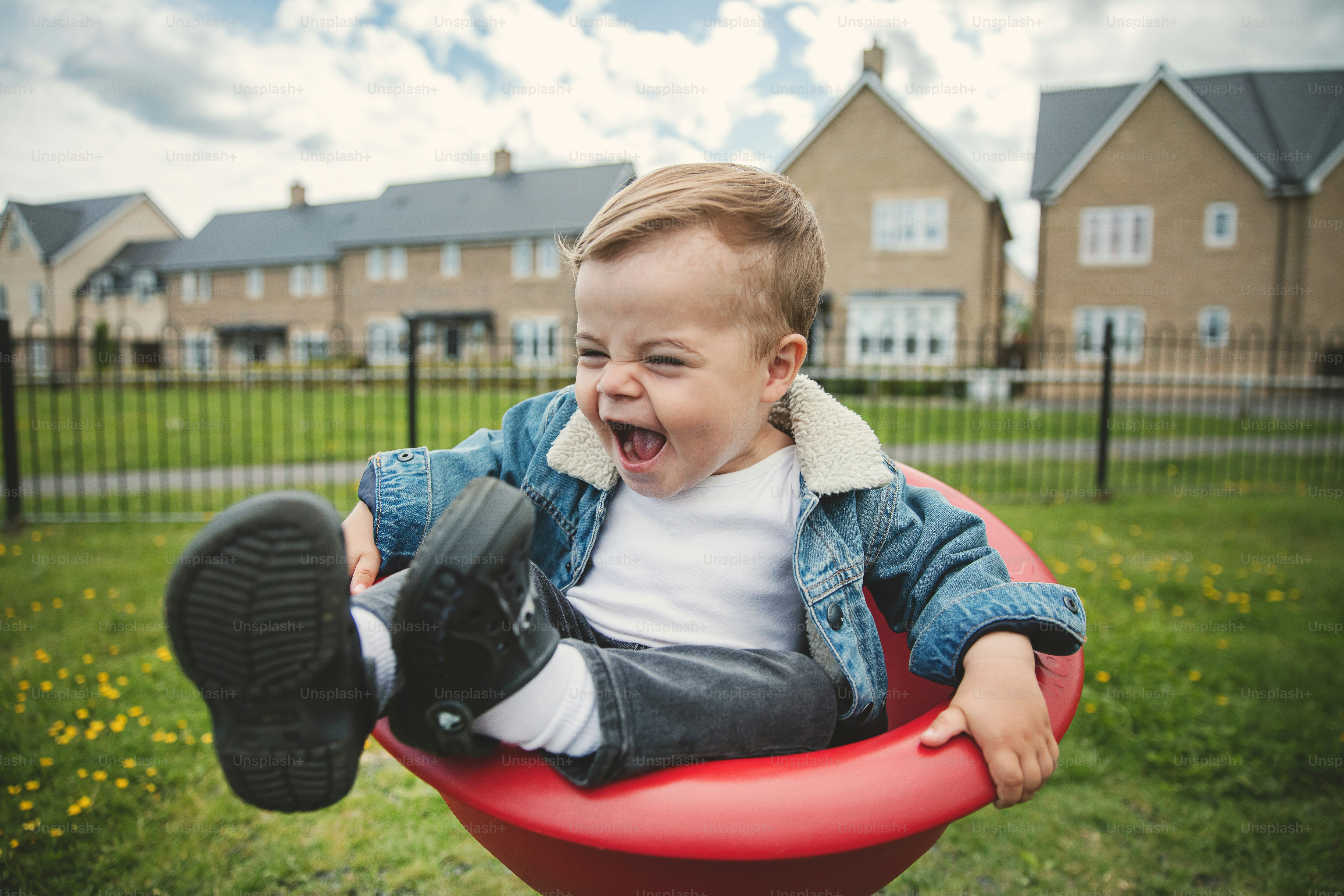 a little boy sitting in a red swing