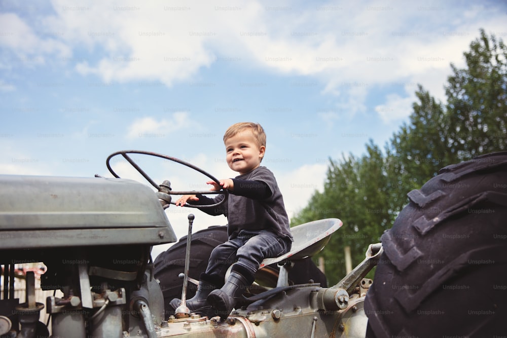 Ein kleiner Junge, der auf dem Rücken eines Traktors fährt