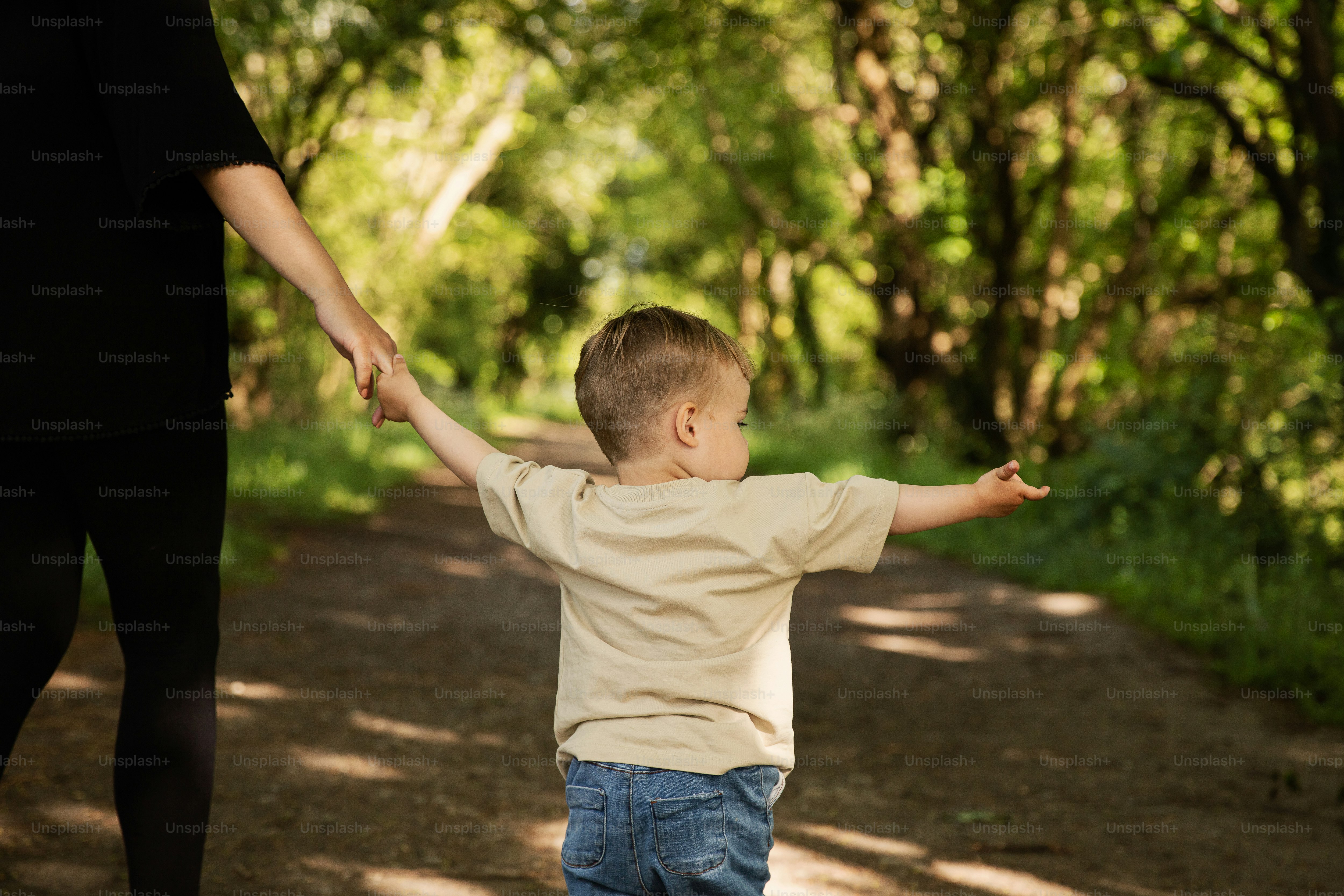 a little boy holding the hand of a woman