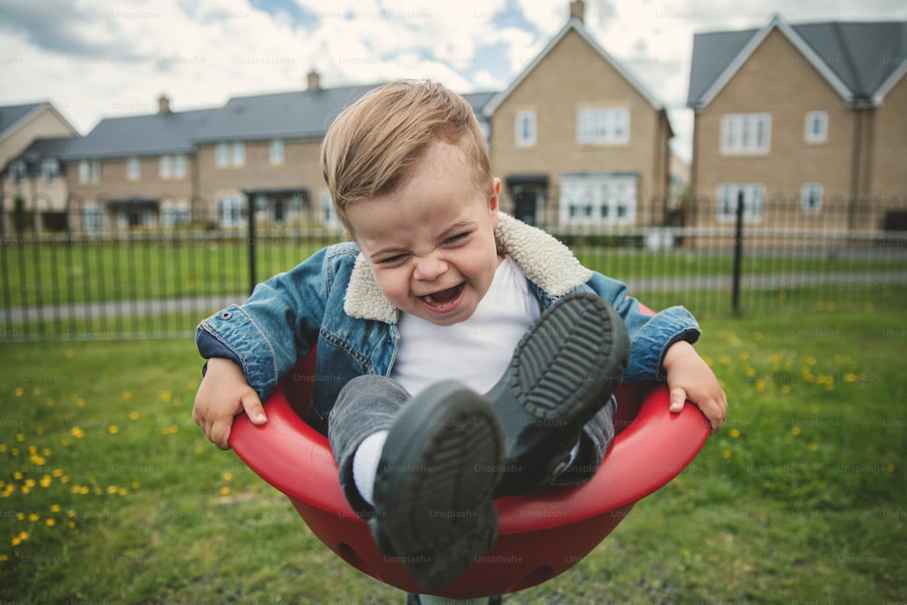 a toddler laughing while sitting in a red chair