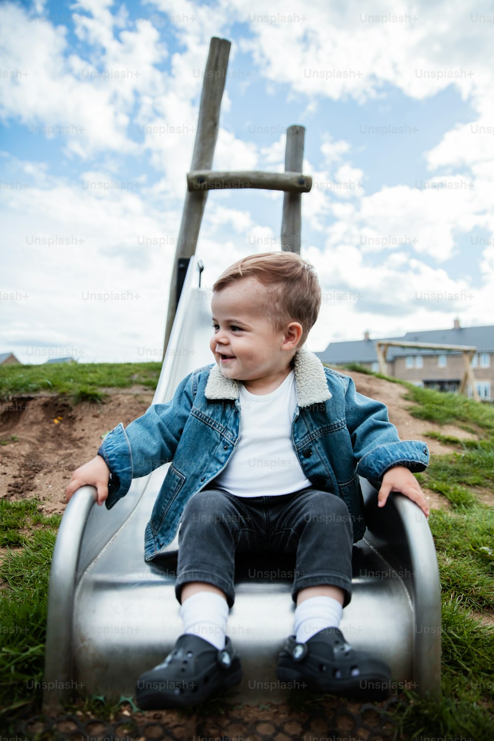a young boy sitting on top of a slide