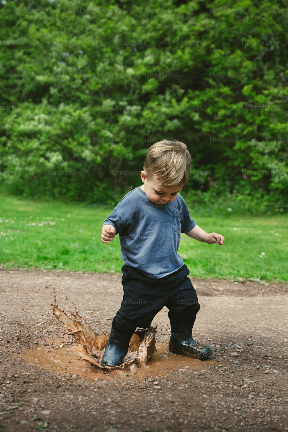 泥の水たまりで遊ぶ少年