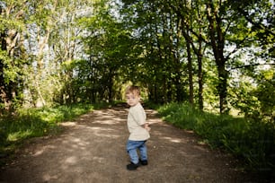 a little boy standing in the middle of a dirt road