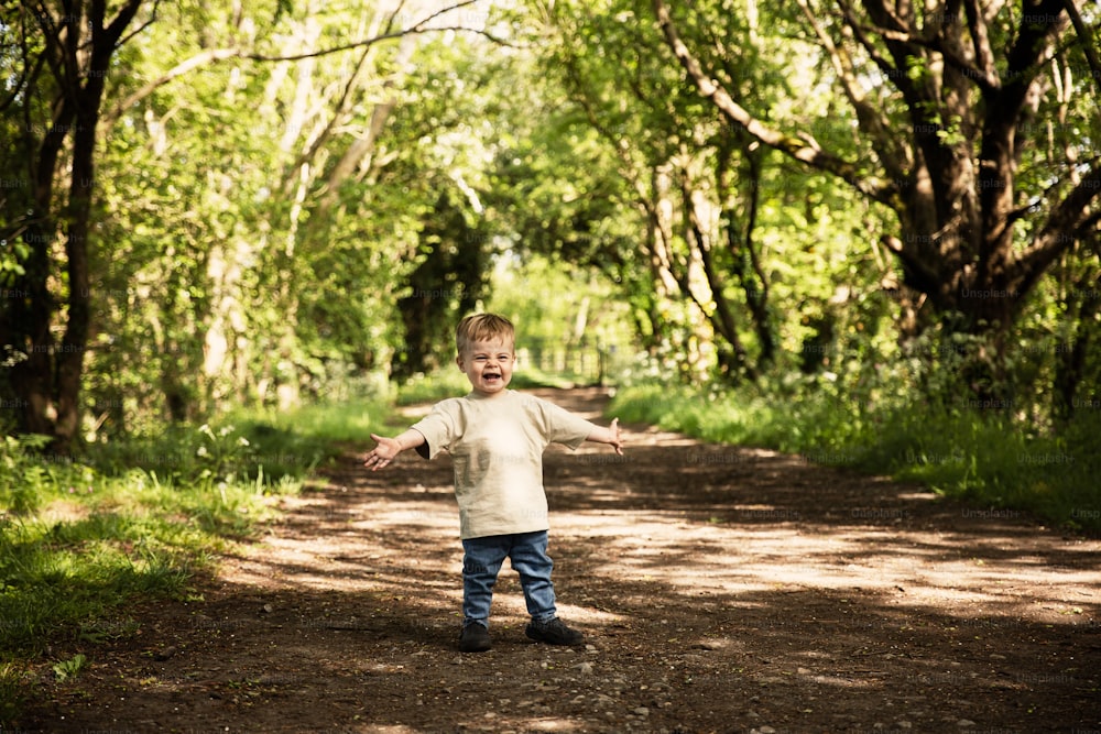 a young boy standing in the middle of a forest