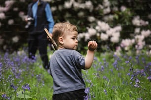 um menino segurando um taco de beisebol em um campo de flores