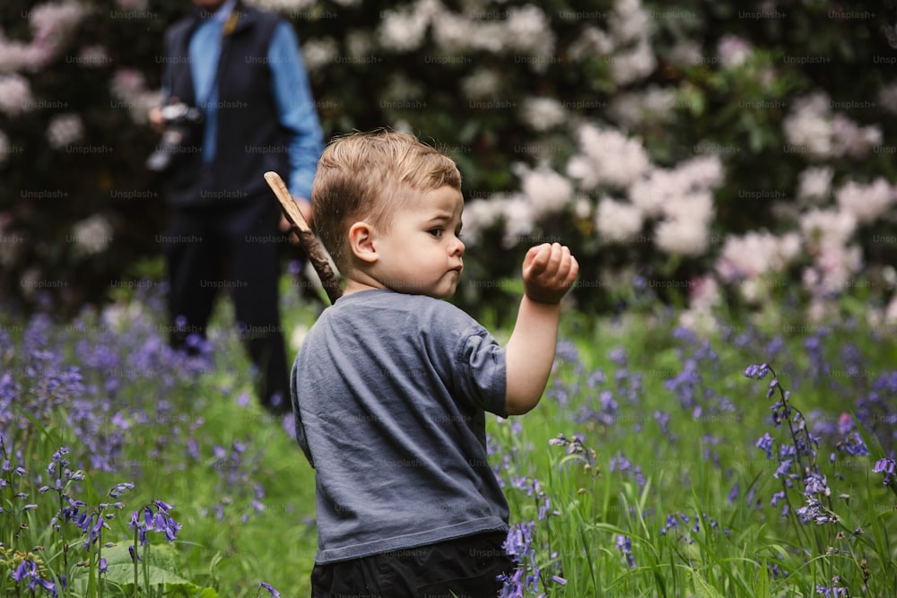 꽃밭에서 야구 방망이를 들고 있는 어린 소년