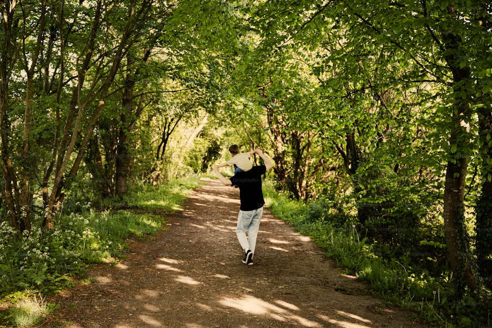 um homem caminhando por uma estrada de terra cercada por árvores