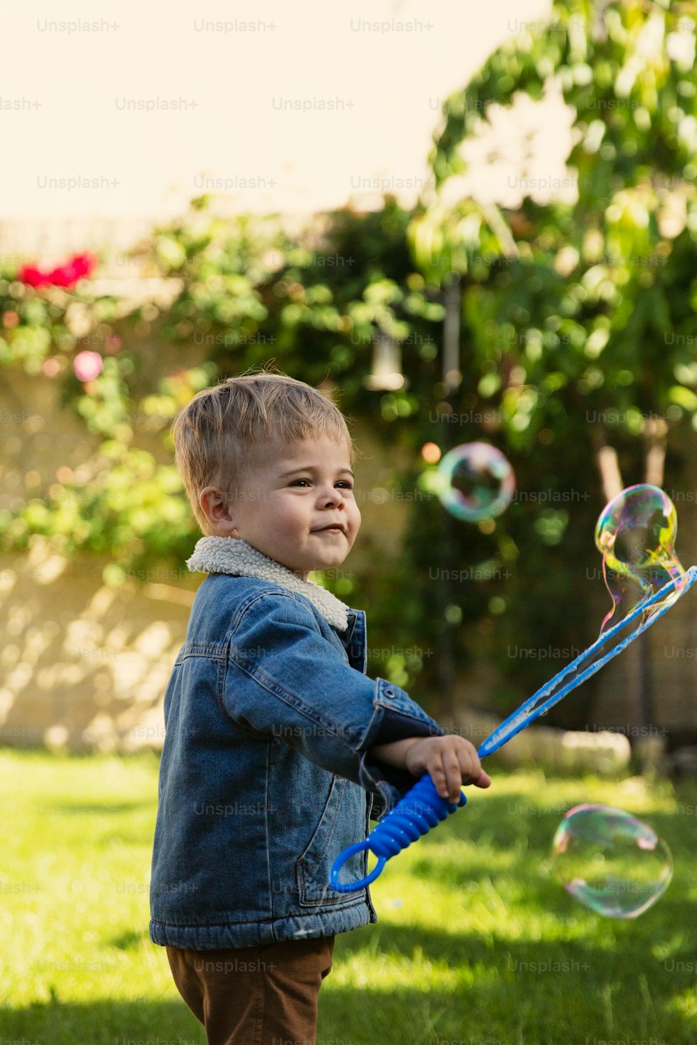 a young boy playing with bubbles in a yard