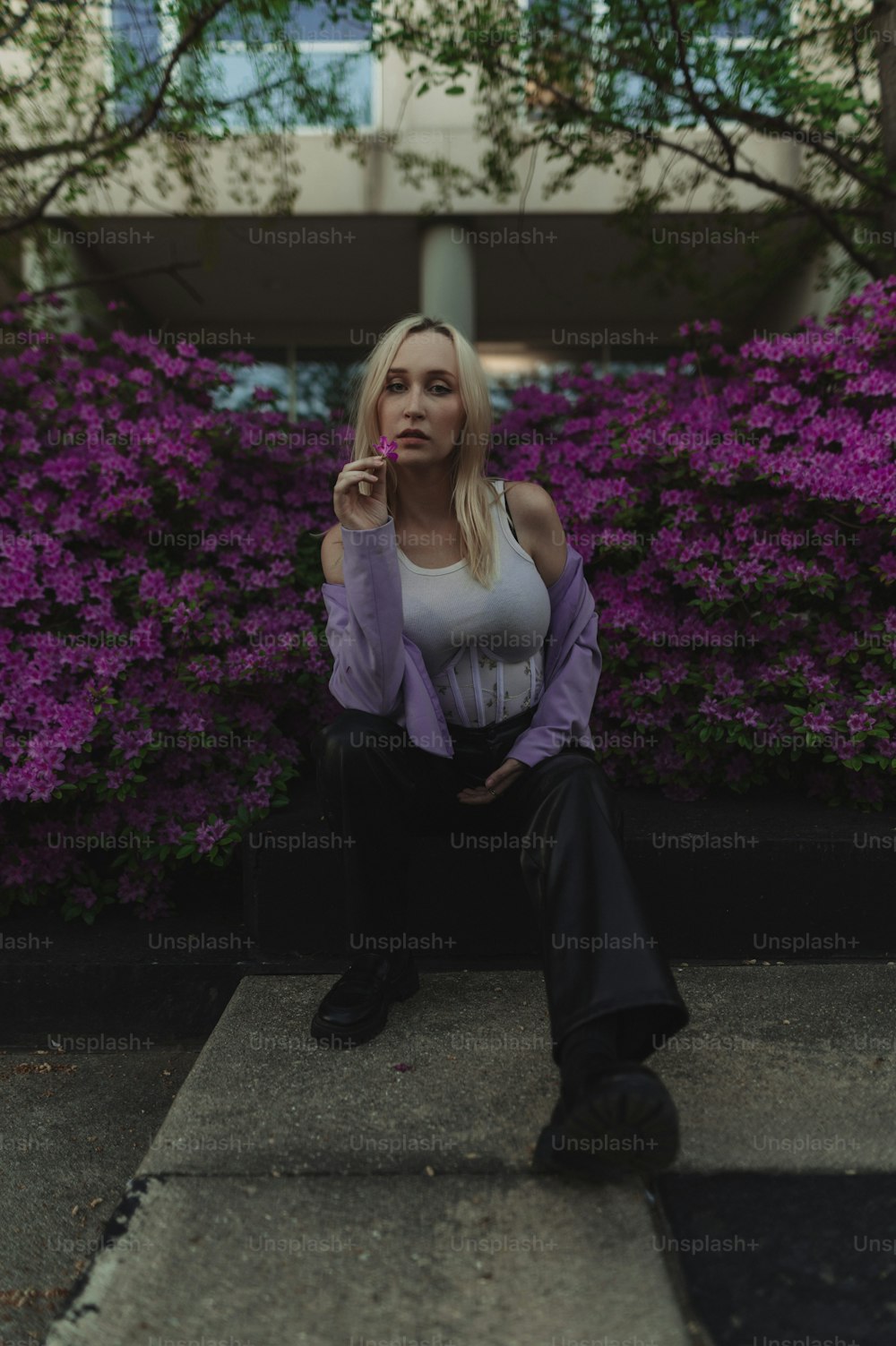 a woman sitting on a step in front of purple flowers