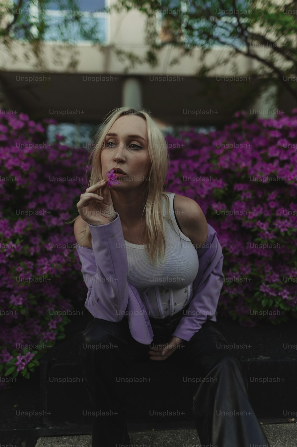 a woman sitting on a bench in front of purple flowers