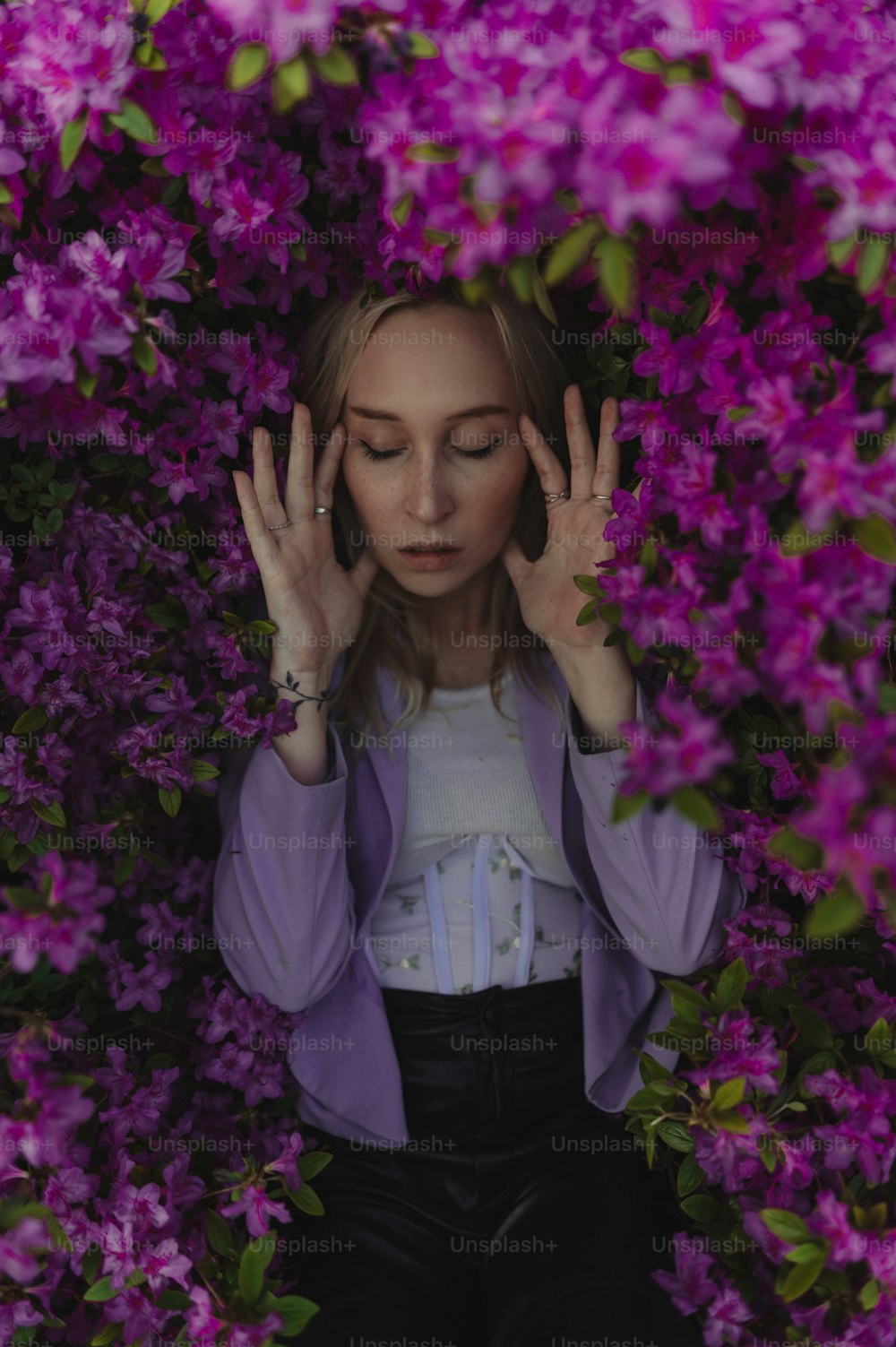 a woman with her hands in the air surrounded by purple flowers